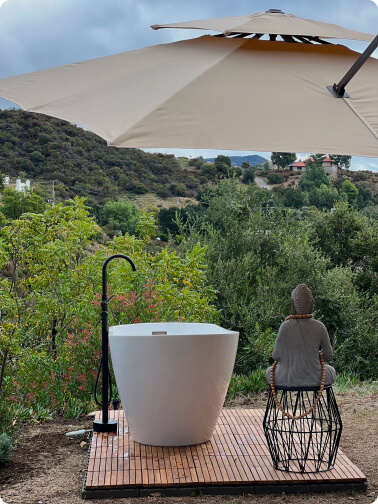 a bath standing on a wooden platform with a view on green mountains under parasol