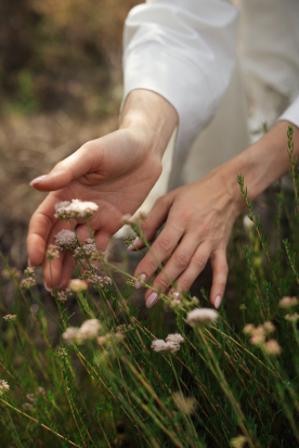 Women's hands next to green flowers