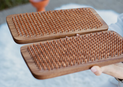 person holds sadhu nail boards with copper nails