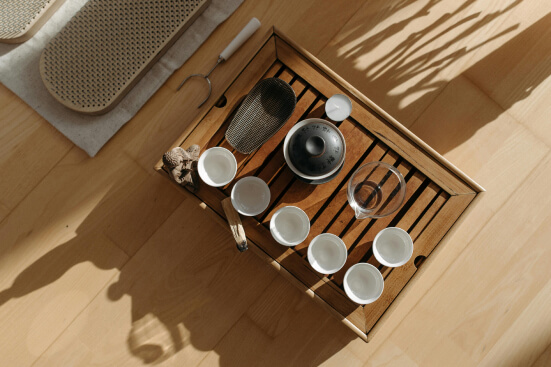 a wooden tray with tea ceremonial instruments and sadhu nail board next to it