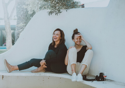 two happy laughing girl seat next to each other