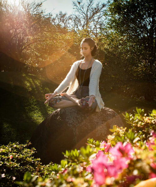 girl is doing meditation on a sunny day among flowers