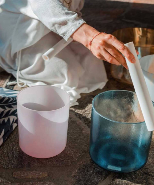 person playing on pink and blue sound healing bowls