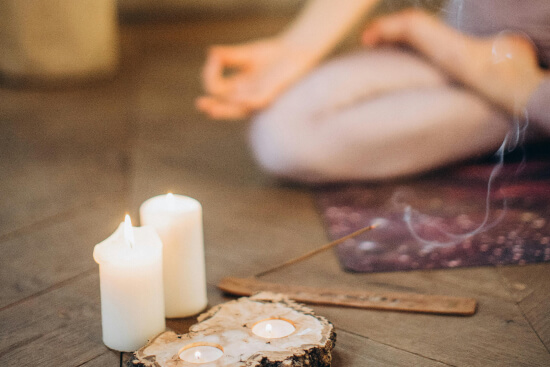 two white candles and a person seats in lotus position