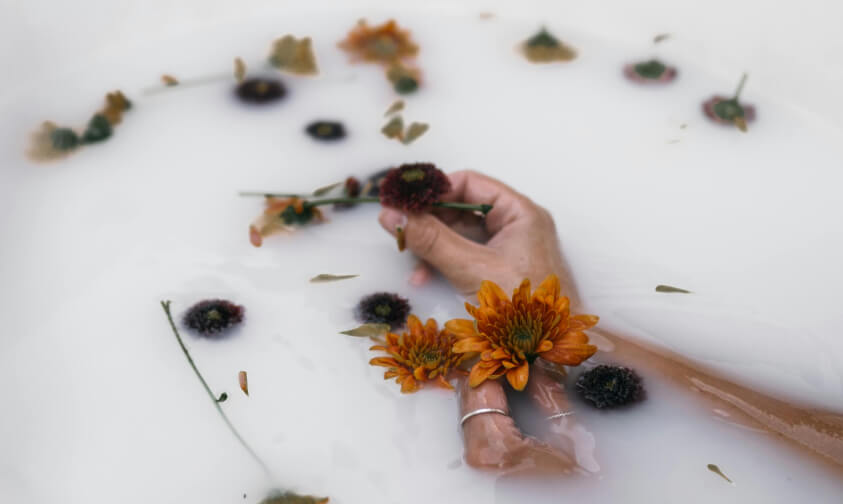 arms in a milky water with flowers