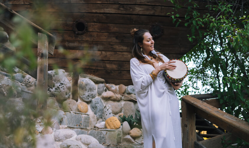 girl is playing meditation drum instruments outdoors