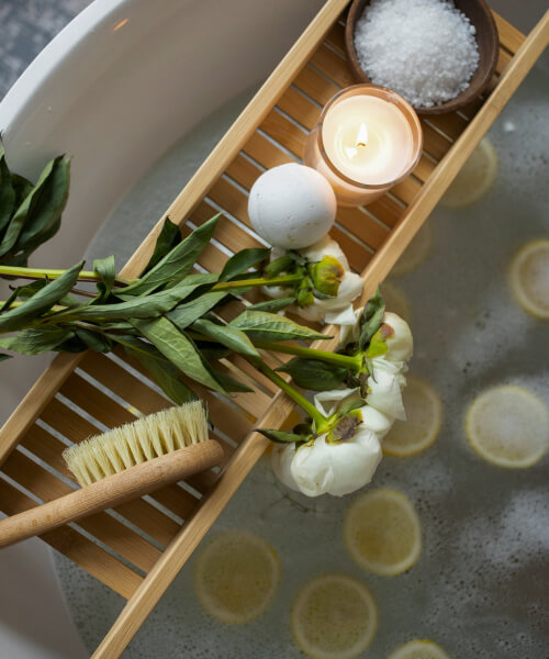 bath full of lemons with a wooden tray standing on top of it with candle and flowers for meditation